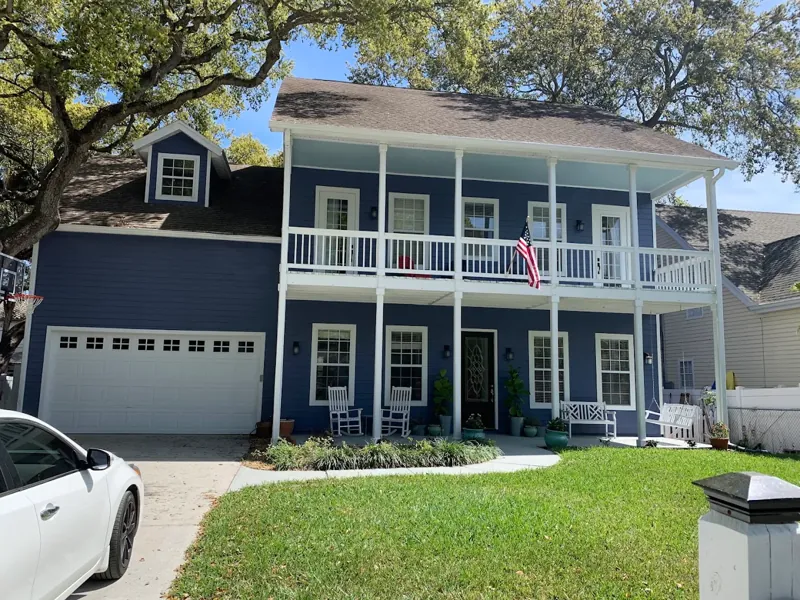 Navy blue two-story home with white trim, a second-floor balcony, and an attached garage.