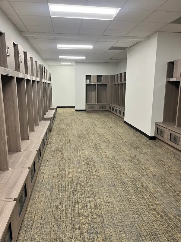 Commercial locker room with wood-tone cubbies and freshly painted white walls.