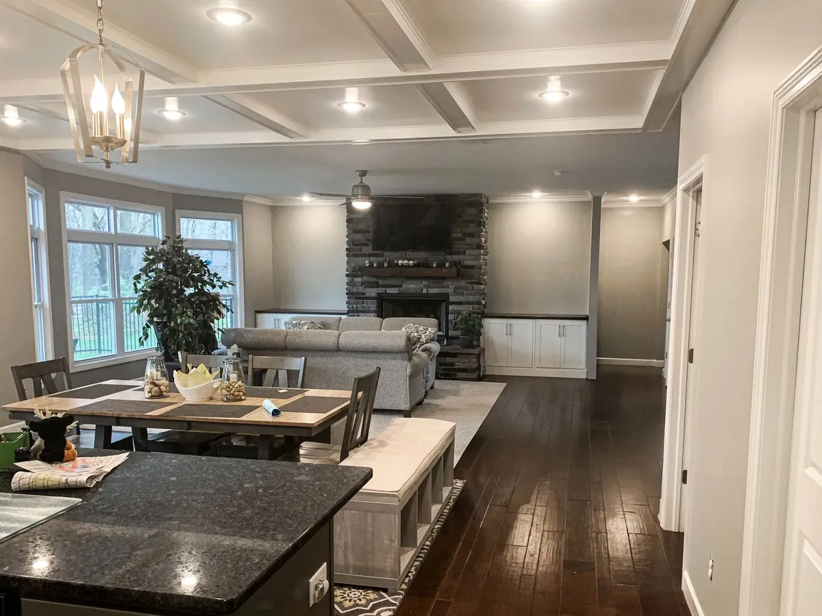 Tampa, FL Full interior repaint of an open-concept living space in Tampa. Our crew painted the walls, coffered ceiling, and kitchen cabinetry surround in a clean neutral gray that ties the living and dining areas together. Two coats of Benjamin Moore Regal Select in eggshell for durability in high-traffic areas.